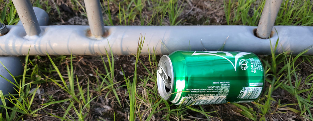 aluminum can litter on the ground near a bike rack